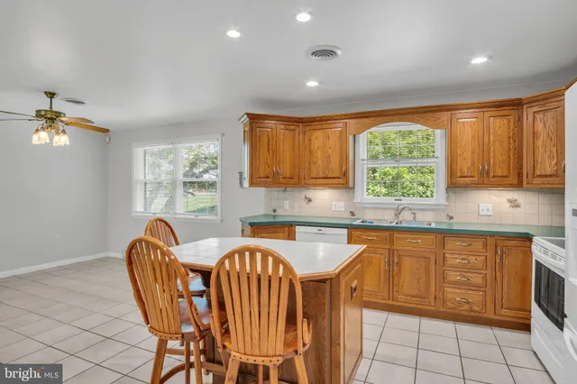 a open kitchen with stainless steel appliances granite countertop a sink a stove a dining table and chairs with wooden floor