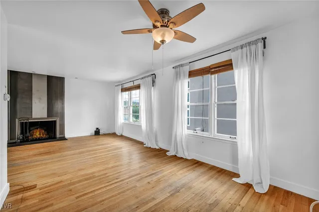 an empty room with wooden floor cabinet and windows