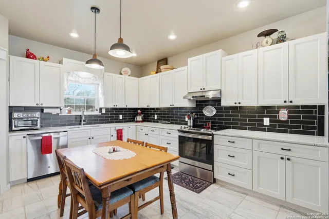a kitchen with granite countertop a sink a cabinets and window stainless steel appliances