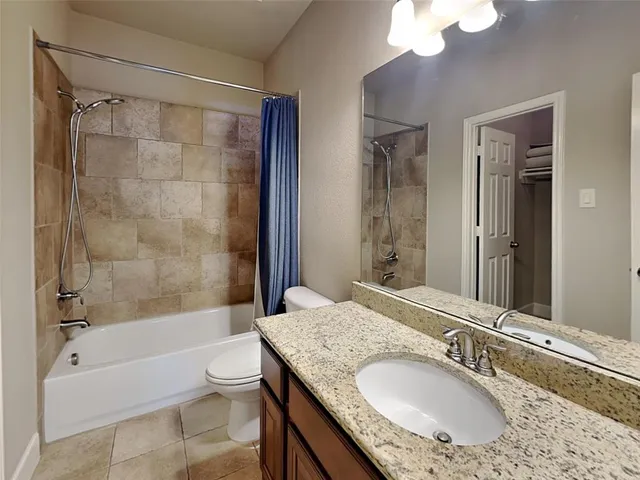a bathroom with a granite countertop sink a toilet and shower