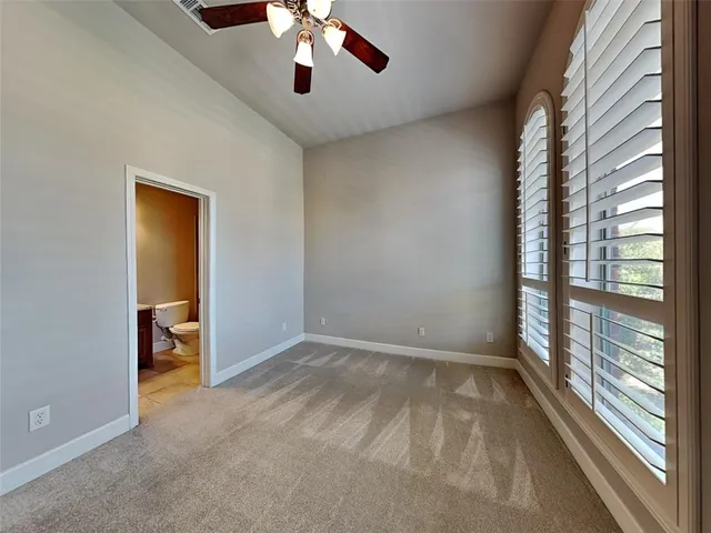 an empty room with chandelier fan and windows
