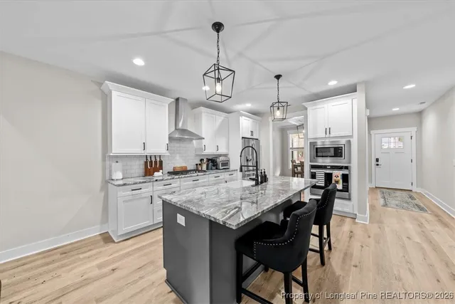 a kitchen with stainless steel appliances granite countertop a kitchen island a stove a table and chairs in it