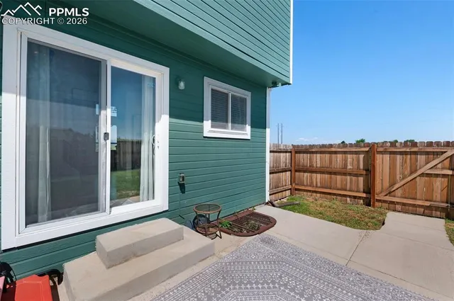 a backyard of a house with wooden fence next to a road