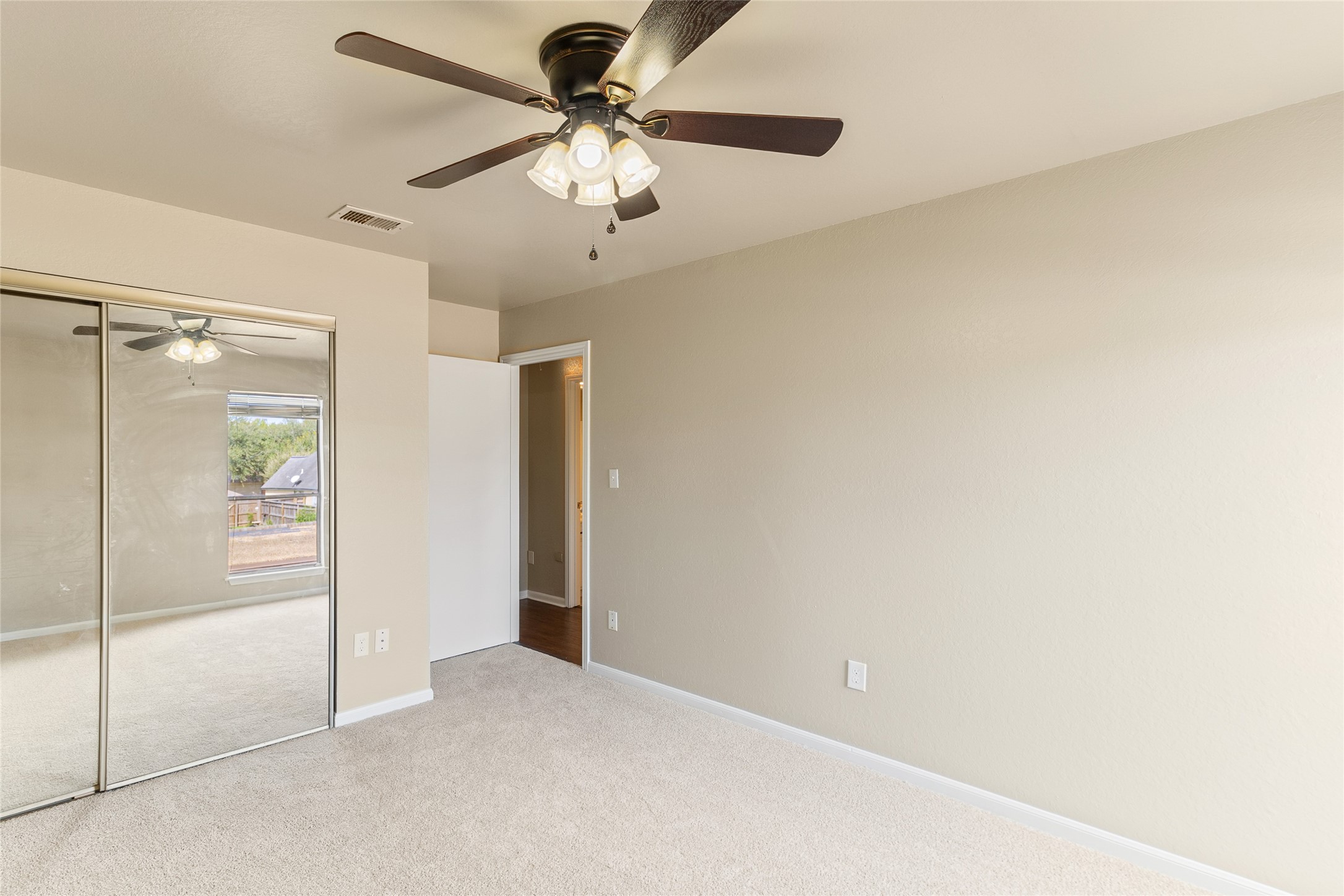 57 South Bachelor Button Street Lake Jackson, TX 77566 - Photo 21 of 29 Another view of Bedroom #2 highlights the mirrored closet doors with built-in dresser storage, combining functionality with a clean, modern look.