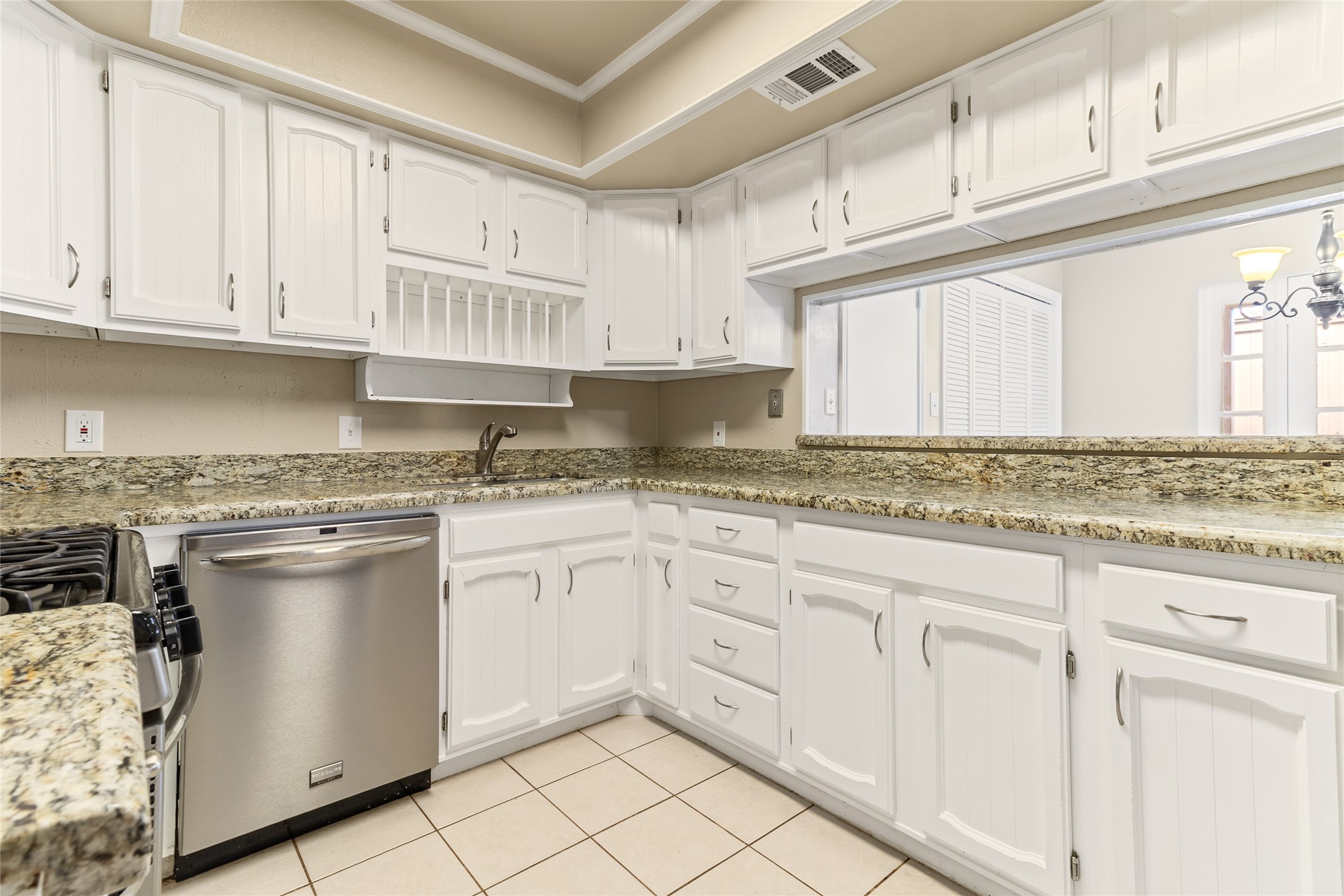 57 South Bachelor Button Street Lake Jackson, TX 77566 - Photo 7 of 29 Kitchen (10x9) features painted wood cabinetry, granite countertops & ample storage—complete with a breakfast bar for casual seating & a clear view of the pantry just beyond.