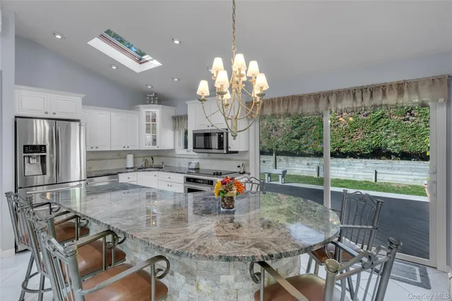 a kitchen with stainless steel appliances granite countertop a stove and a view of dining room