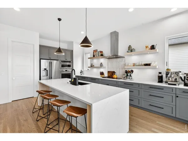 a kitchen with stainless steel appliances kitchen island granite countertop a sink a stove and a wooden floors
