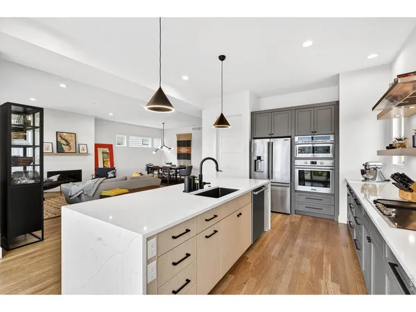 a large kitchen with kitchen island a stove a sink a refrigerator and a wooden floor