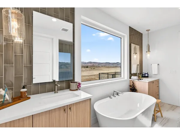 a bathroom with a double vanity sink a large mirror and a bathtub