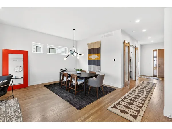 a view of a dining room and livingroom with furniture wooden floor a rug a rug a fireplace and a chandelier