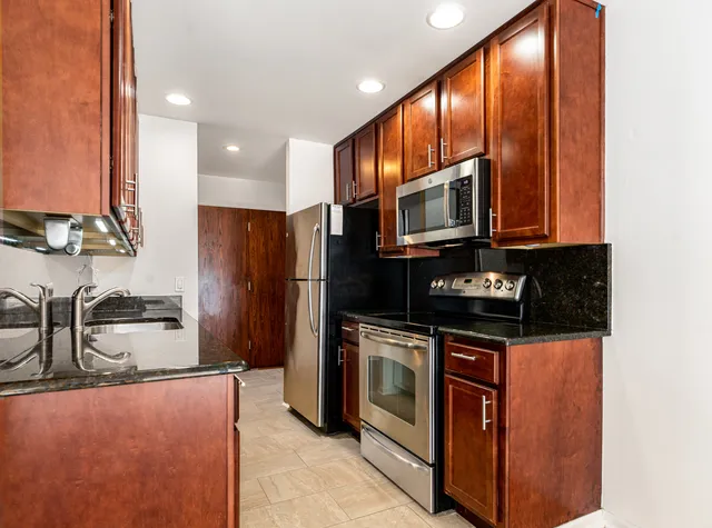 a kitchen with stainless steel appliances granite countertop a stove a sink and a microwave