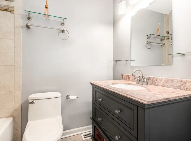 a bathroom with a granite countertop sink a toilet and a mirror