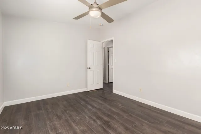 an empty room with wooden floor and fan