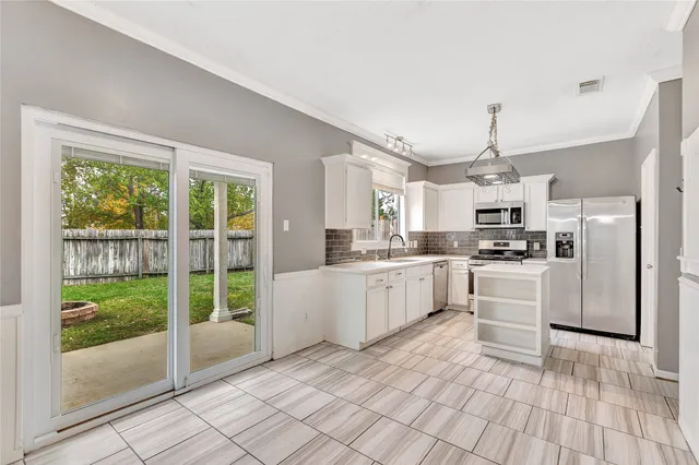 a kitchen with white cabinets and window