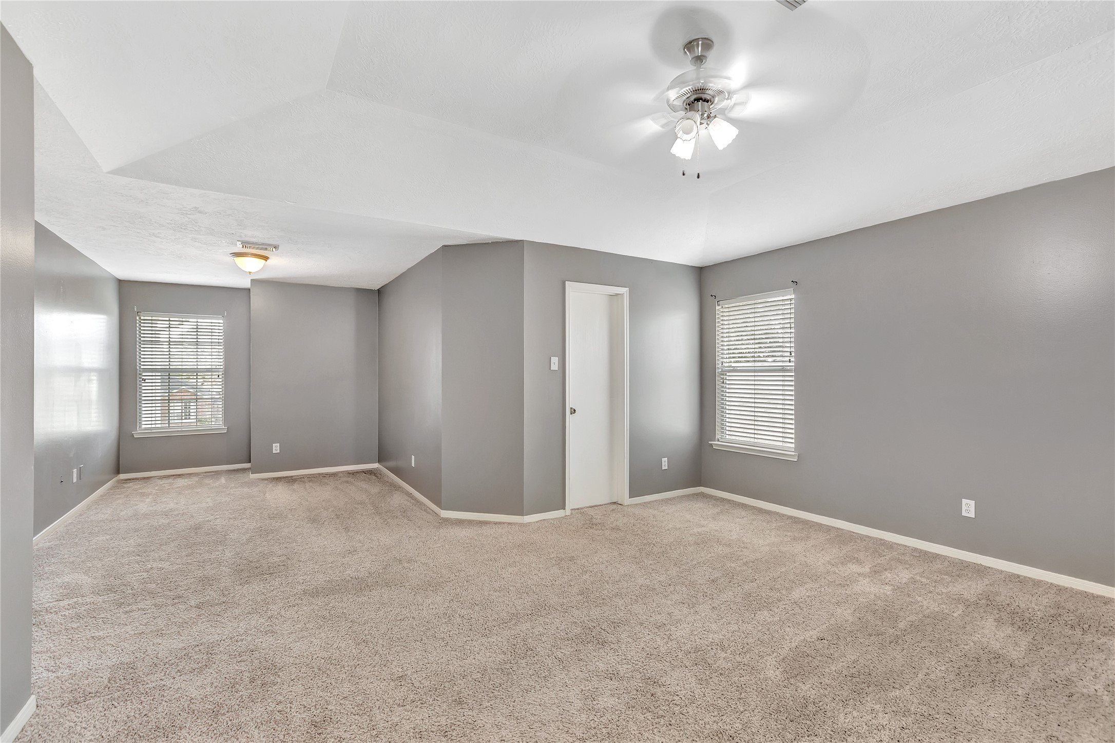 1007 Addison Park Lane Spring, TX 77373 - Photo 14 of 24 This spacious primary bedroom boasts soft carpeting, elegant gray walls, and ample natural light, creating a serene and inviting retreat.