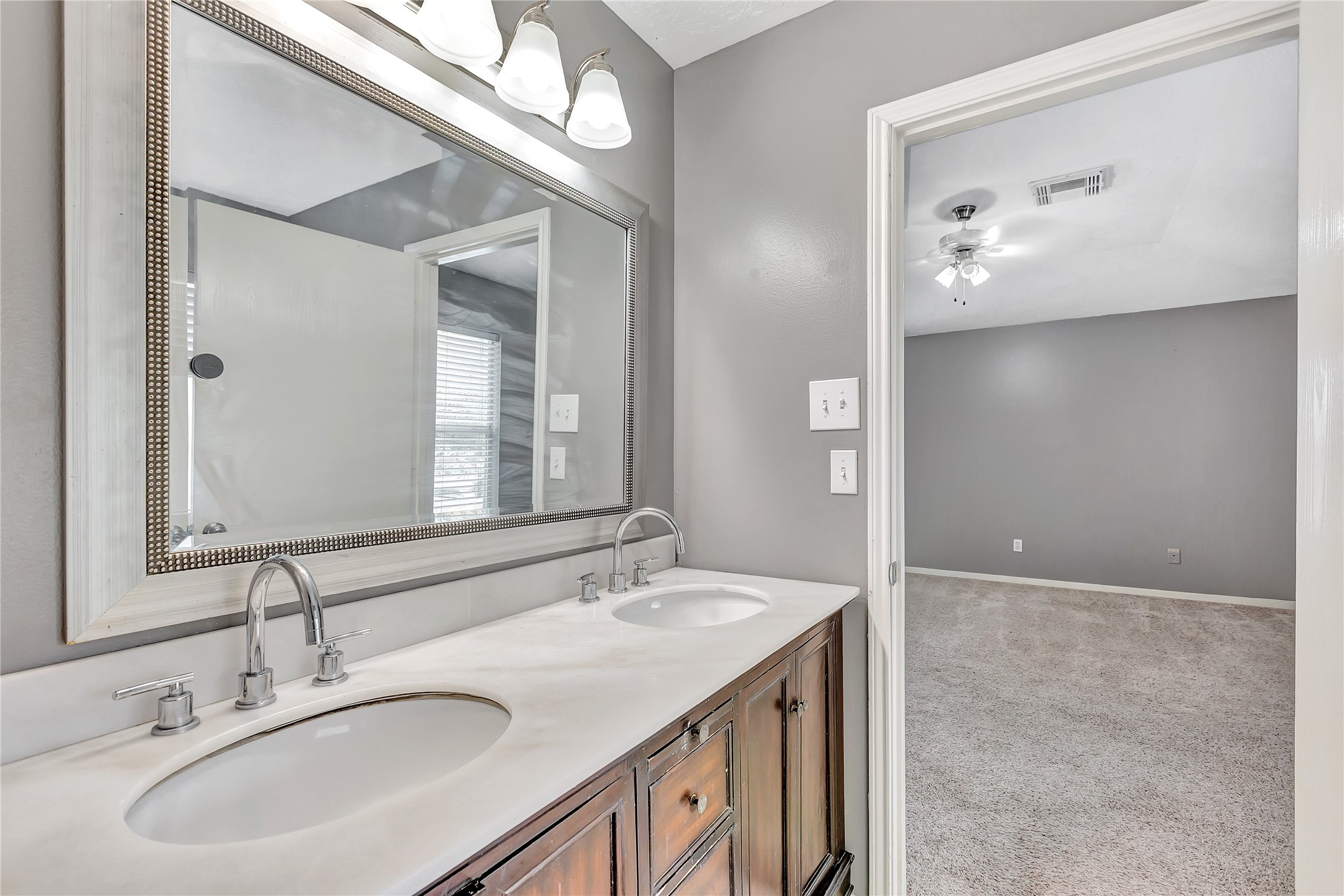 1007 Addison Park Lane Spring, TX 77373 - Photo 19 of 24 This spacious primary bathroom offers a serene retreat with soft gray walls, plush carpeting, and ample natural light streaming through large windows, creating a perfect blend of comfort and elegance.
