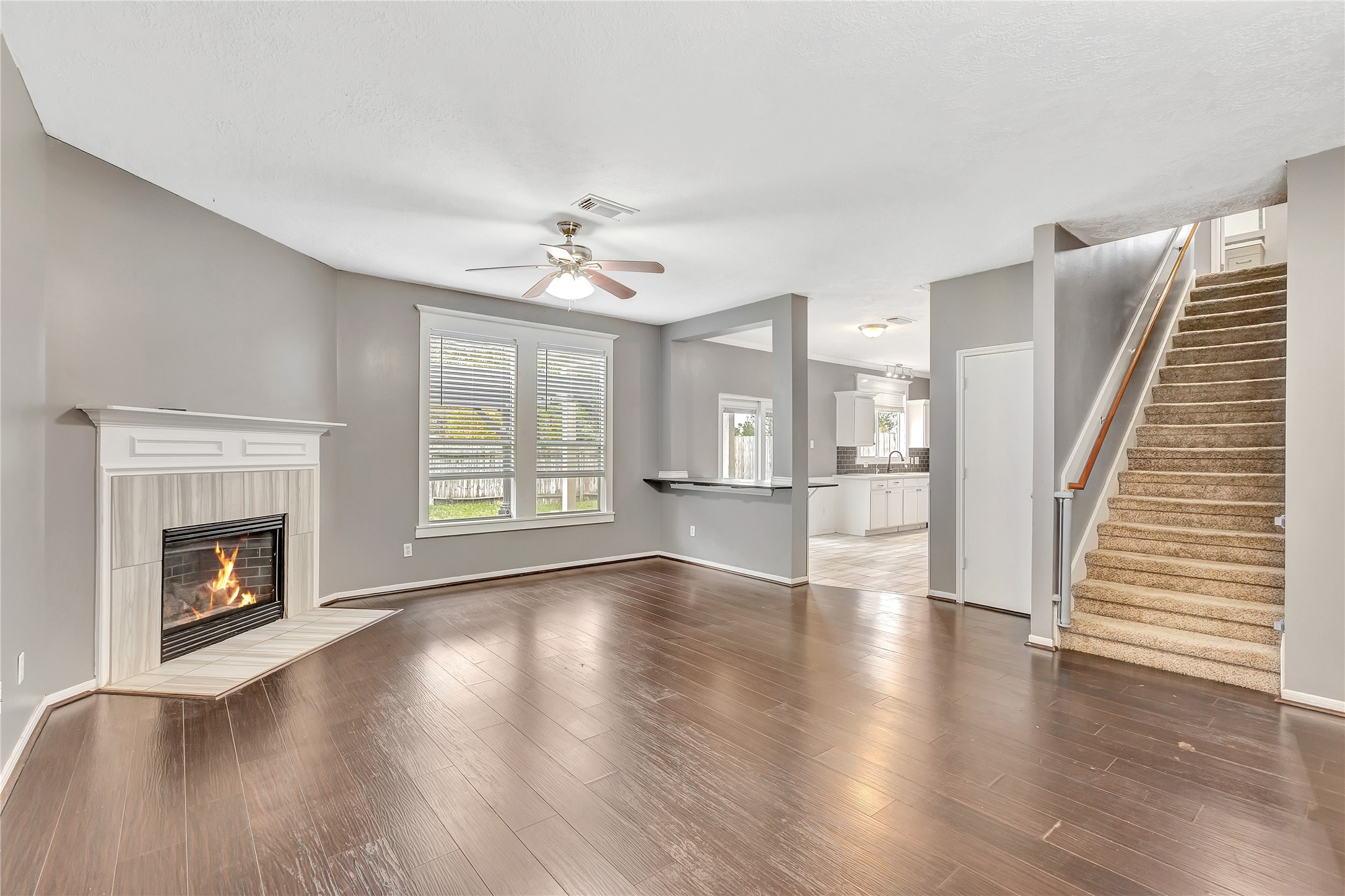 1007 Addison Park Lane Spring, TX 77373 - Photo 4 of 24 This inviting living room features elegant hardwood floors, a cozy fireplace, and a seamless flow into the kitchen, with an adjoining staircase adding charm and connectivity.