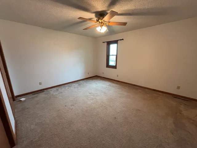 an empty room with windows and fan