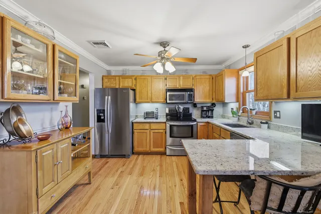 a kitchen with stainless steel appliances granite countertop a refrigerator a stove top oven a sink dishwasher and wooden cabinets with wooden floor