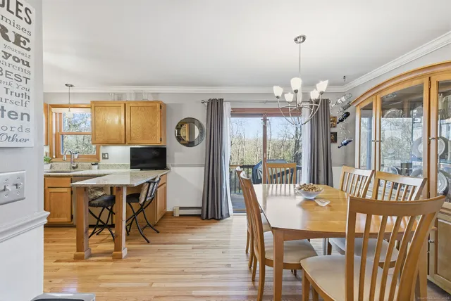 a dining room with wooden floor a chandelier a wooden table and chairs