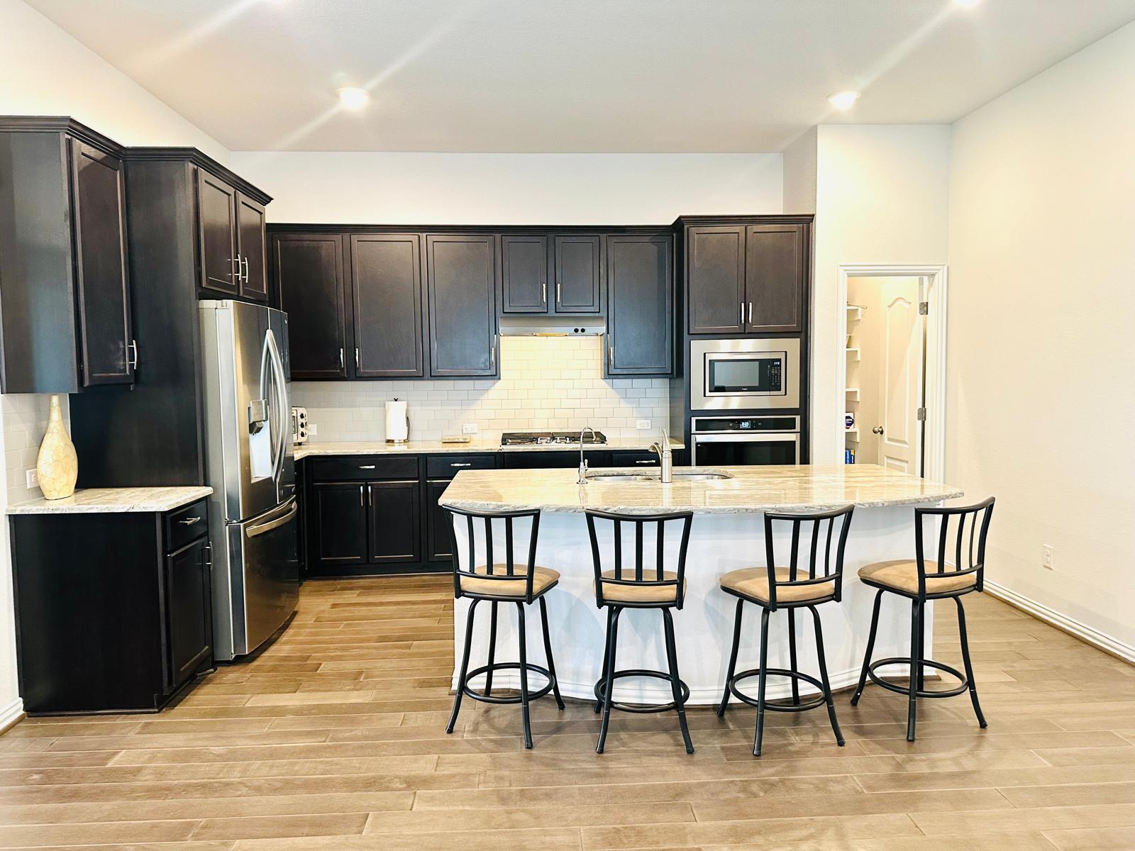 862 Leadtree Loop Buda, TX 78610 - Photo 16 of 40 a kitchen with stainless steel appliances granite countertop a stove a refrigerator a sink a dining table and chairs