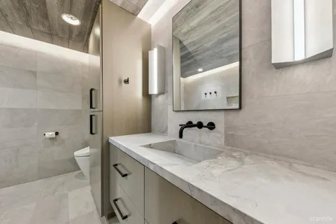 a bathroom with a granite countertop sink a toilet and a mirror