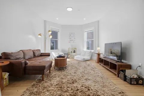 a living room with furniture a flat screen tv and windows