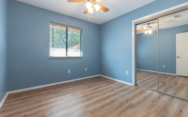 a view of an empty room with window and wooden floor