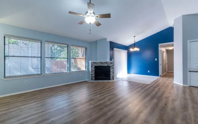 a view of an empty room with a window and wooden floor