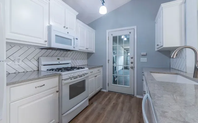 a kitchen with granite countertop a sink stainless steel appliances and cabinets