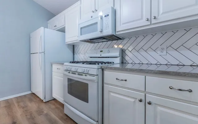 a kitchen with white cabinets and white appliances
