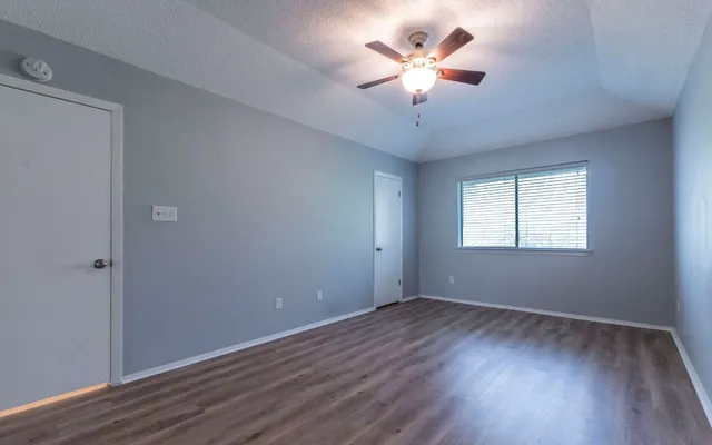 a view of a room with wooden floor and a ceiling fan