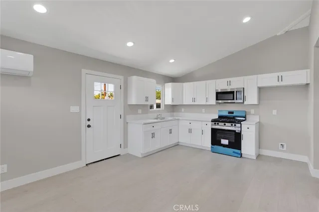 a large white kitchen with cabinets stove and a sink