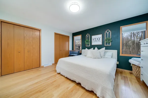 a bed sitting in a spacious bedroom next to a window