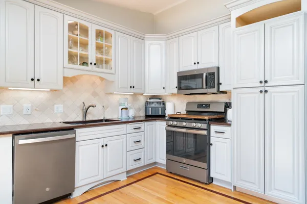 a kitchen with granite countertop white cabinets and stainless steel appliances