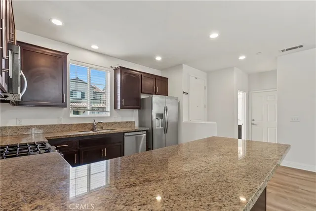a kitchen with stainless steel appliances granite countertop a sink stove and refrigerator