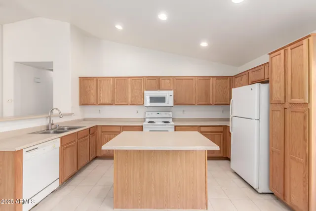 a kitchen with stainless steel appliances granite countertop a stove top oven a sink a refrigerator and white cabinets with wooden floor