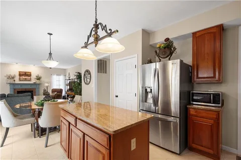 a kitchen with stainless steel appliances granite countertop a refrigerator a sink dishwasher a stove and a dining table with wooden floor