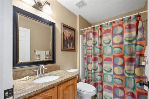 a bathroom with a granite countertop sink a toilet and a mirror
