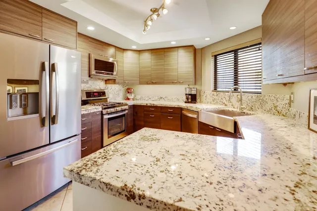 a kitchen with stainless steel appliances granite countertop a stove a sink a refrigerator white cabinets and wooden floor