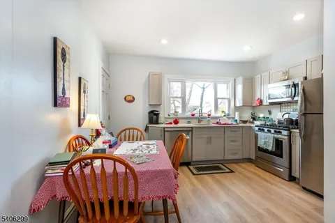 a kitchen with stainless steel appliances granite countertop a sink a stove a refrigerator cabinets and living room view