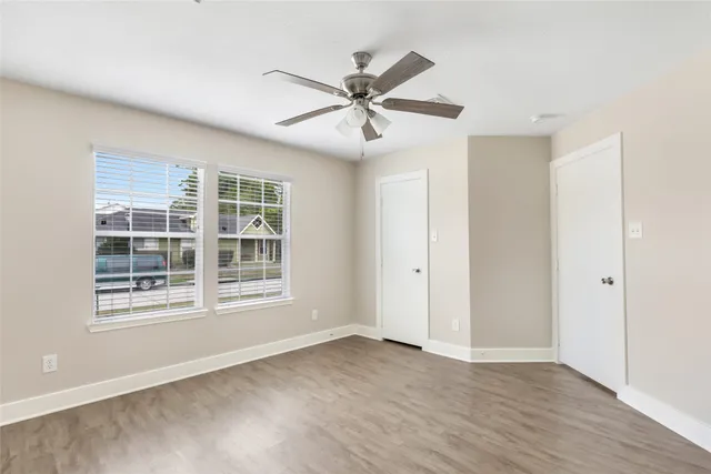 a view of an empty room with a window and wooden floor