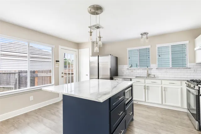 a large kitchen with kitchen island a large counter top space a sink stainless steel appliances and windows