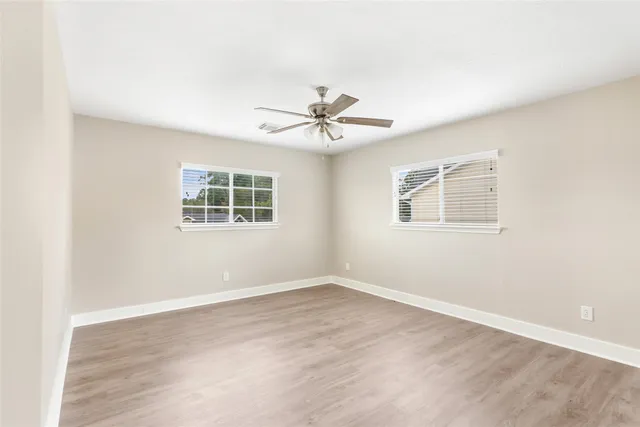 an empty room with wooden floor and windows