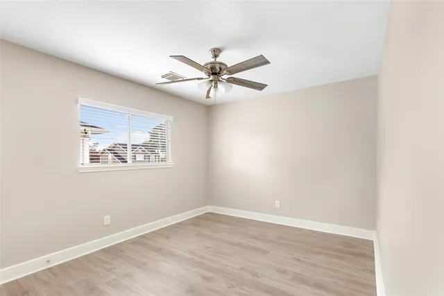 an empty room with a window and a fan