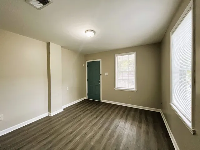 a view of an empty room with wooden floor and a window