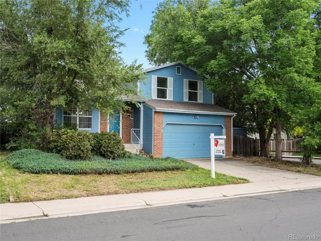 a front view of a house with a garden and trees