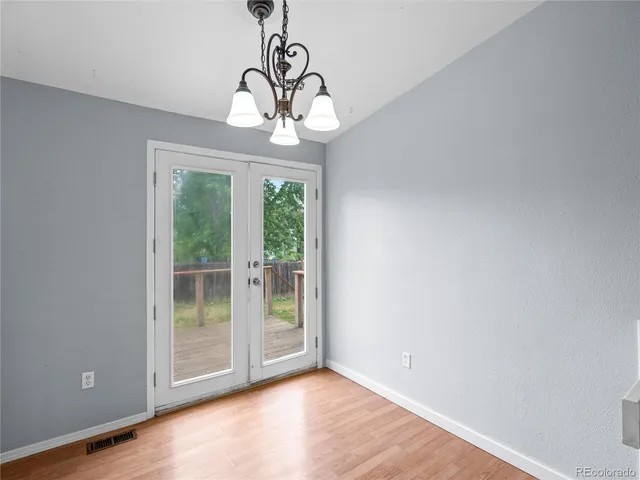 a view of a livingroom with a chandelier wooden floor and windows