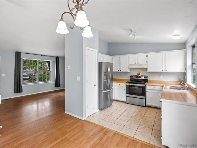 a kitchen with granite countertop a refrigerator stove top oven and sink