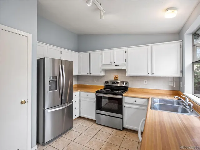 a kitchen with stainless steel appliances granite countertop a refrigerator sink and stove